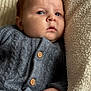 baby, infant, face, portrait, knitted_sweater, grey_clothing, wooden_buttons, blanket, soft_texture, cozy, resting, closeup, skin, hand, indoor, child, young_baby, warm, comfort, sleepy