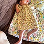baby, brown_quilt, cozy, cute, diaper, floral_blanket, floral_dress, foot, hand, head, indoors, infant, lying_down, newborn, pacifier, peaceful, person, resting, skin, sleeping
