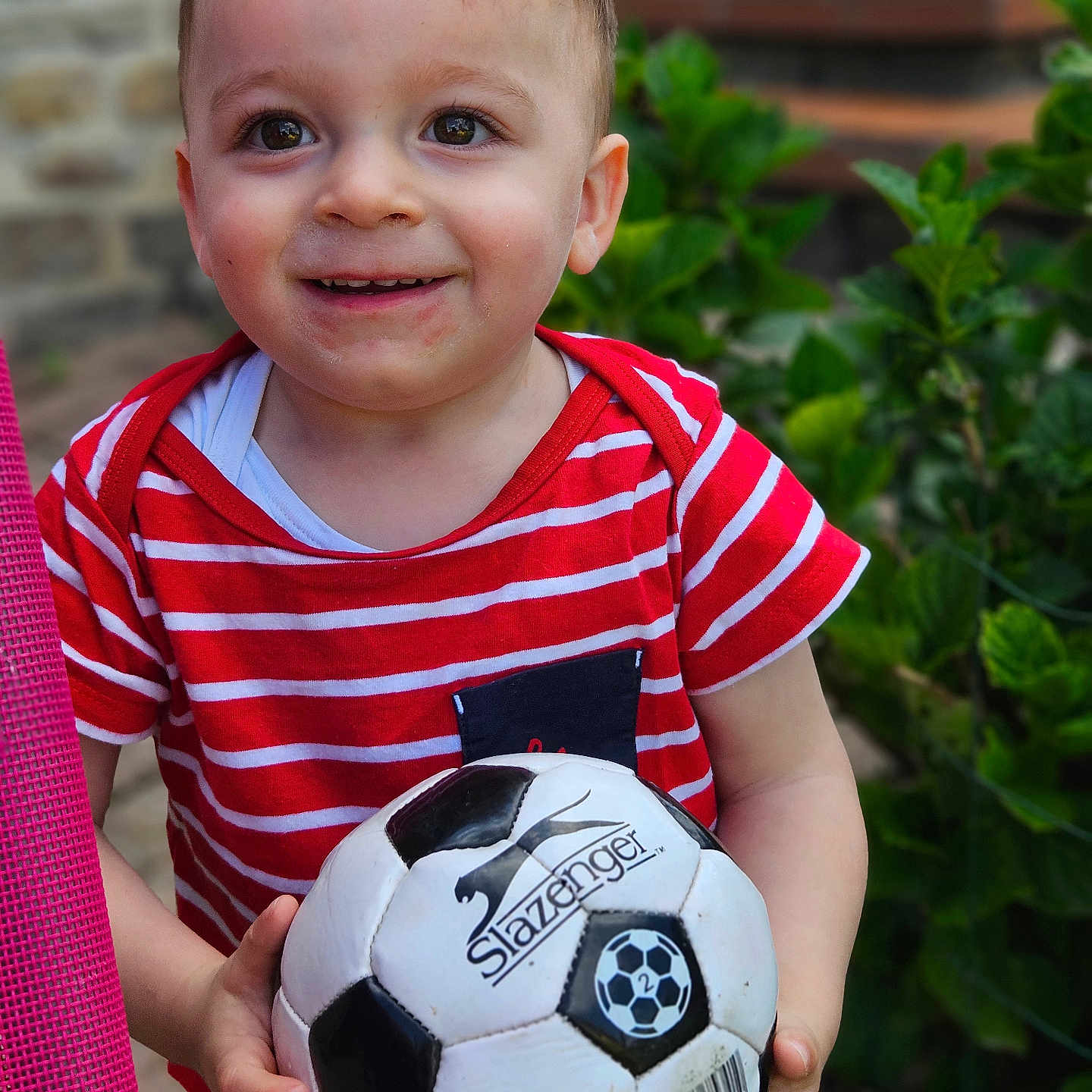 Martin a rejoint le concours — aidez-le/la à gagner de superbes lots ! background, boy, casual_clothing, child, daylight, face, greenery, hands, happy, nature, outdoor, person, playing, portrait, red_striped_shirt, short_hair, smiling, soccer_ball, sport, toy