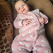 Raya joined the competition — help win amazing prizes! baby, infant, onesie, pink, hearts, couch, blanket, cushion, indoor, soft, comfortable, relaxed, person, child, face, hands, clothing, portrait, resting, cozy