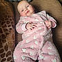 baby, infant, onesie, pink, hearts, couch, blanket, cushion, indoor, soft, comfortable, relaxed, person, child, face, hands, clothing, portrait, resting, cozy