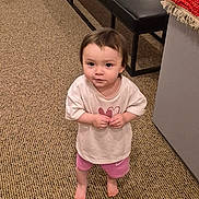 Fia joined the competition — help win amazing prizes! toddler, child, indoor, carpet, barefoot, curious, pink_shorts, white_tshirt, bench, textile, colorful, floor, standing, young_child, person, portrait, looking_up, casual_clothing, room, home