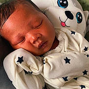 O'Mari is registered to the contest to win money with this photo: newborn, baby, sleeping, plush_toy, onesie, star_pattern, cozy, cute, child, infant, soft_toy, peaceful, resting, closeup, indoor, portrait, head, face, relaxation, comfort