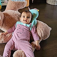 Rose a rejoint le concours — aidez-le/la à gagner de superbes lots ! baby, boots, child, comfort, cute, decorations, face, felt_tree, floor, indoor, person, pink_clothing, playroom, plush_toy, relaxing, smiling, teddy_bear, toy_basket, wooden_floor, young_child