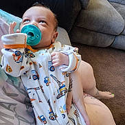 Ragnar joined the competition — help win amazing prizes! baby, pacifier, onesie, infant, person, couch, carpet, hand, foot, tattoo, clothing, indoor, cute, child, face, looking_up, holding, fabric, sleeve, comfort