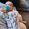 baby, pacifier, onesie, infant, person, couch, carpet, hand, foot, tattoo, clothing, indoor, cute, child, face, looking_up, holding, fabric, sleeve, comfort
