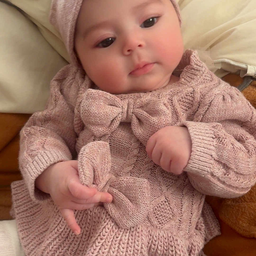 Auriella is registered to the contest to win money with this photo: baby, blanket, bow, child, closeup, cozy, cushion, cute, headband, indoors, infant, knitwear, person, pink, portrait, resting, soft, sweater, tights, warm