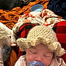 Auriella is registered to the contest to win money with this photo: baby, bedroom, blanket, child, comfort, cozy, dog, face, indoor, infant, knitted_hat, pacifier, person, plush, red_and_black_checkered, relaxation, resting, sleeping, soft_lighting, warm_colors