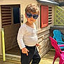 Tiago a rejoint le concours — aidez-le/la à gagner de superbes lots ! child, sunglasses, playhouse, outdoor, wooden_deck, red_chair, blue_chair, plastic_furniture, sunlight, casual_clothing, pants, long_sleeve_shirt, play, smile, person, boy, shadow, summer, daylight, fun
