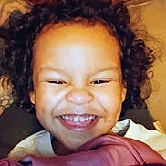 Marcus joined the competition — help win amazing prizes! blanket, casual_clothing, child, closeup, cozy, curly_hair, cute, expression, face, hand, happy, indoor, joyful, person, portrait, relaxed, sitting, smiling, warm_lighting, young_child