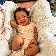 Skyler joined the competition — help win amazing prizes! baby, smiling, infant, blanket, cozy, indoors, cute, happy, child, clothing, socks, curly_hair, person, portrait, relaxed, home, soft_texture, infant_girl, resting, toddler