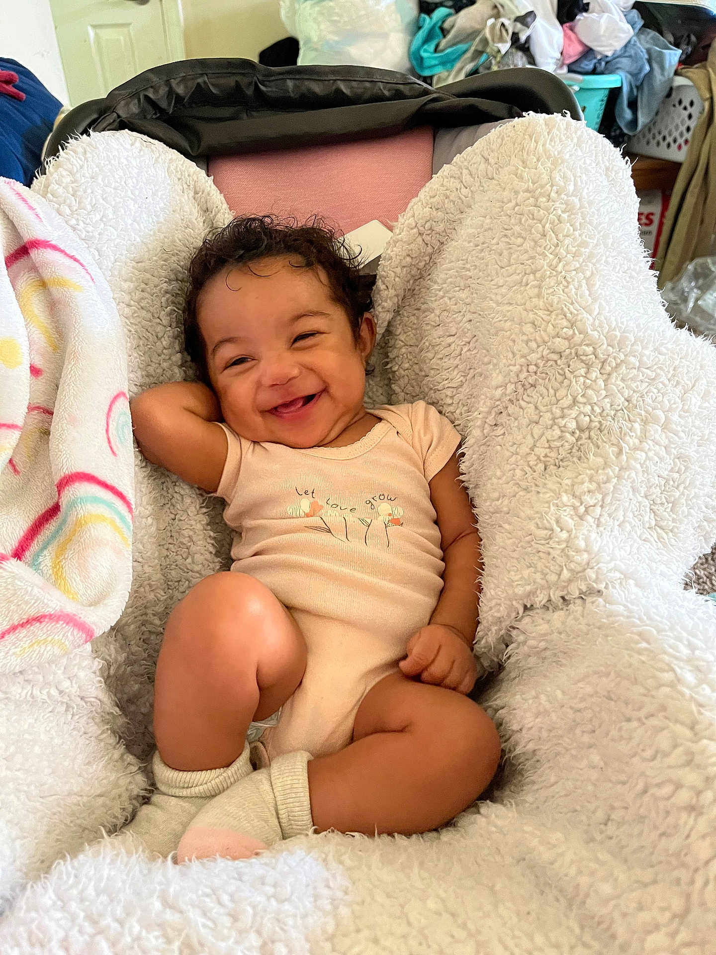 Skyler joined the competition — help win amazing prizes! baby, smiling, infant, blanket, cozy, indoors, cute, happy, child, clothing, socks, curly_hair, person, portrait, relaxed, home, soft_texture, infant_girl, resting, toddler