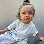 Raphaël a rejoint le concours — aidez-le/la à gagner de superbes lots ! blue_eyes, casual, child, curious, cute, daylight, hair_up, light_skin, neutral_background, outdoor, person, portrait, shorts, sitting, smiling, toddler, topknot, white_tshirt, woven_surface, young_child