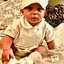 Shiloh joined the competition — help win amazing prizes! baby, child, infant, white_outfit, chef_hat, bed, pillow, patterned_pillow, box, barcode, curious, sitting, indoors, soft_lighting, cute, small_hands, footwear, blanket, close_up, portrait