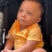 Shiloh is registered to the contest to win money with this photo: baby, child, stroller, yellow_shirt, cute, infant, sitting, hands, expression, face, eyes, clothing, comfort, portrait, casual, indoors, soft_light, closeup, young, adorable