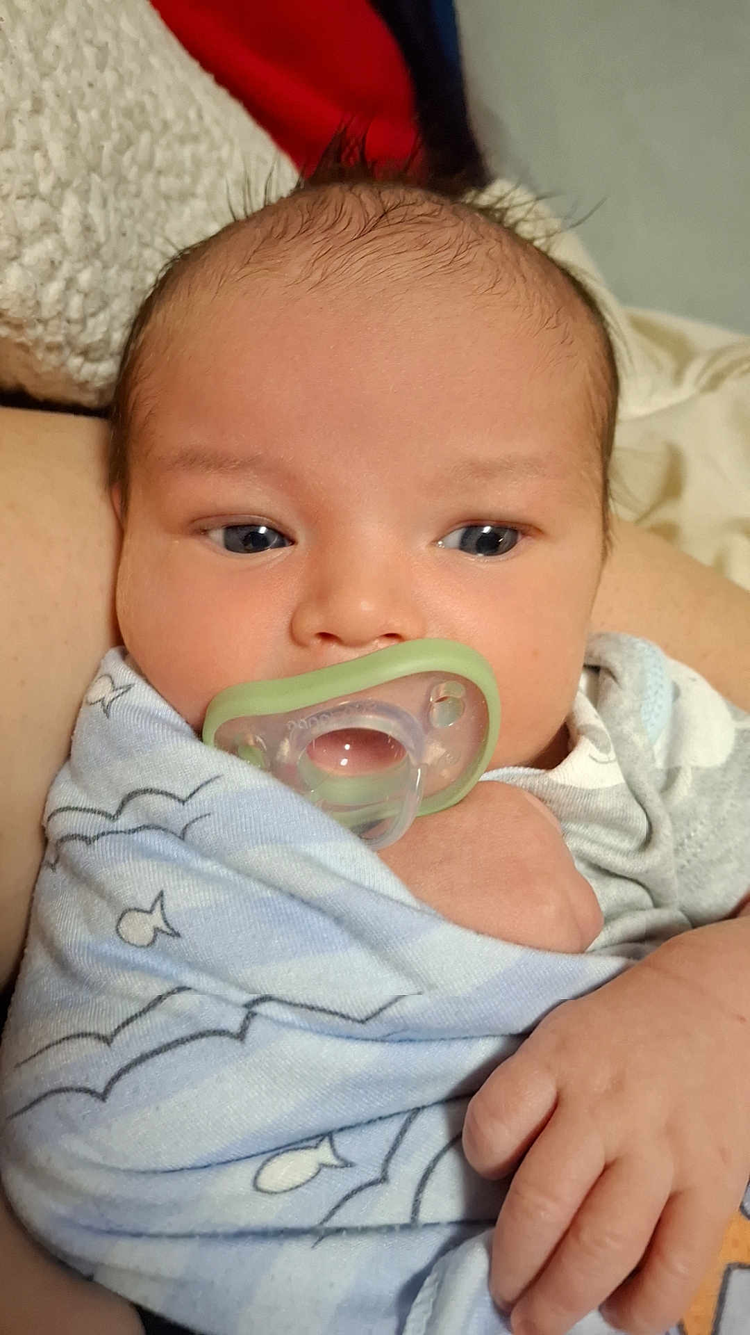 Malik is registered to the contest to win money with this photo: baby, pacifier, blanket, infant, closeup, hand, face, sleepy, wrapped, newborn, cute, child, soft, skin, comfort, lying_down, indoors, blue, pattern, peaceful