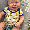 baby, child, smile, onesie, giraffe_pattern, baby_seat, infant, cute, happy, sitting, clothing, face, arm, hand, furniture, indoor, colorful, pattern, skin, portrait