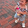 baby, bottle, brick_pavement, child, curly_hair, cute, daylight, fun, happy, joyful, outdoor, person, pink_lid, playful, shorts, smiling, summer_clothing, toddler, walking, white_shoes