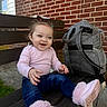 backpack, bench, blue_jeans, brick_wall, casual_clothing, child, concrete, cute, daylight, grass, hair_clips, happy, outdoor, person, pink_boots, pink_sweater, playful, sitting, smiling, toddler