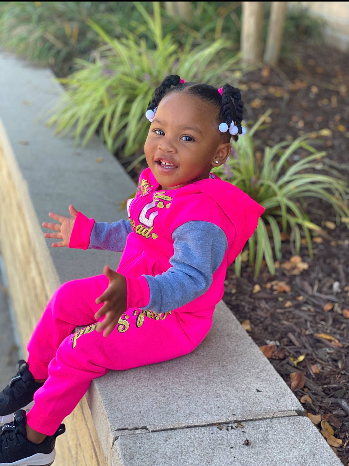 Avah is registered to the contest to win money with this photo: baby, baby_toddler_clothing, child, clothing, fun, grass, happy, joy, leisure, magenta, person, pink, plant, purple, recreation, sandal, sitting, sleeve, smile, t_shirt