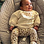 baby, infant, sitting, quilted_seat, gray, cream_sweater, leopard_print_pants, socks, face, happy_expression, indoor, clothing, child, cute, portrait, cozy, soft_lighting, fabric, seat, hands
