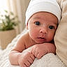 Alexander is registered to the contest to win money with this photo: baby, infant, newborn, hat, white_hat, blanket, soft_texture, neutral_colors, indoor, portrait, cute, face, skin, hands, resting, lying_down, cozy, closeup, curious, child