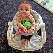 Logan joined the competition — help win amazing prizes! baby, child, infant, toy, baby_seat, colorful, patterned_carpet, looking_up, curious_expression, indoor, hands, feet, clothing, playtime, soft_focus, cute, adorable, seated, home, young