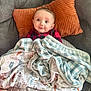 Logan is registered to the contest to win money with this photo: baby, blanket, cushion, red_plaid, orange_pillow, armchair, cute, smile, cozy, indoor, person, child, footwear, soft_toys, patterned_blanket, head, face, comfort, happy, toddler
