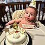 baby, birthday_cake, high_chair, party_hat, sprinkles, candle, cake, face, child, indoor, celebration, cream, cherry, furniture, person, hat, table, expression, seat, background