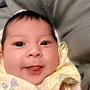 Gracelynn is registered to the contest to win money with this photo: baby, infant, face, eyes, tongue, yellow_clothing, floral_pattern, close_up, cute, smiling, soft_texture, blanket, resting, skin, head, portrait, newborn, child, cozy, happy