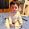 Gracelynn is registered to the contest to win money with this photo: baby, child, infant, onesie, bed, blue_bedspread, sun_pattern, curly_hair, indoors, wooden_wall, pajamas, cute, person, portrait, sitting, soft_toys, blanket, home, curious, young