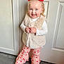 Darcey is registered to the contest to win money with this photo: blue_eyes, child, clothing, cute, door, fashion, faux_fur_vest, flooring, hair_buns, happy, heart_pattern, indoor, person, pink_pants, portrait, red_bows, smiling, standing, toddler, white_shirt