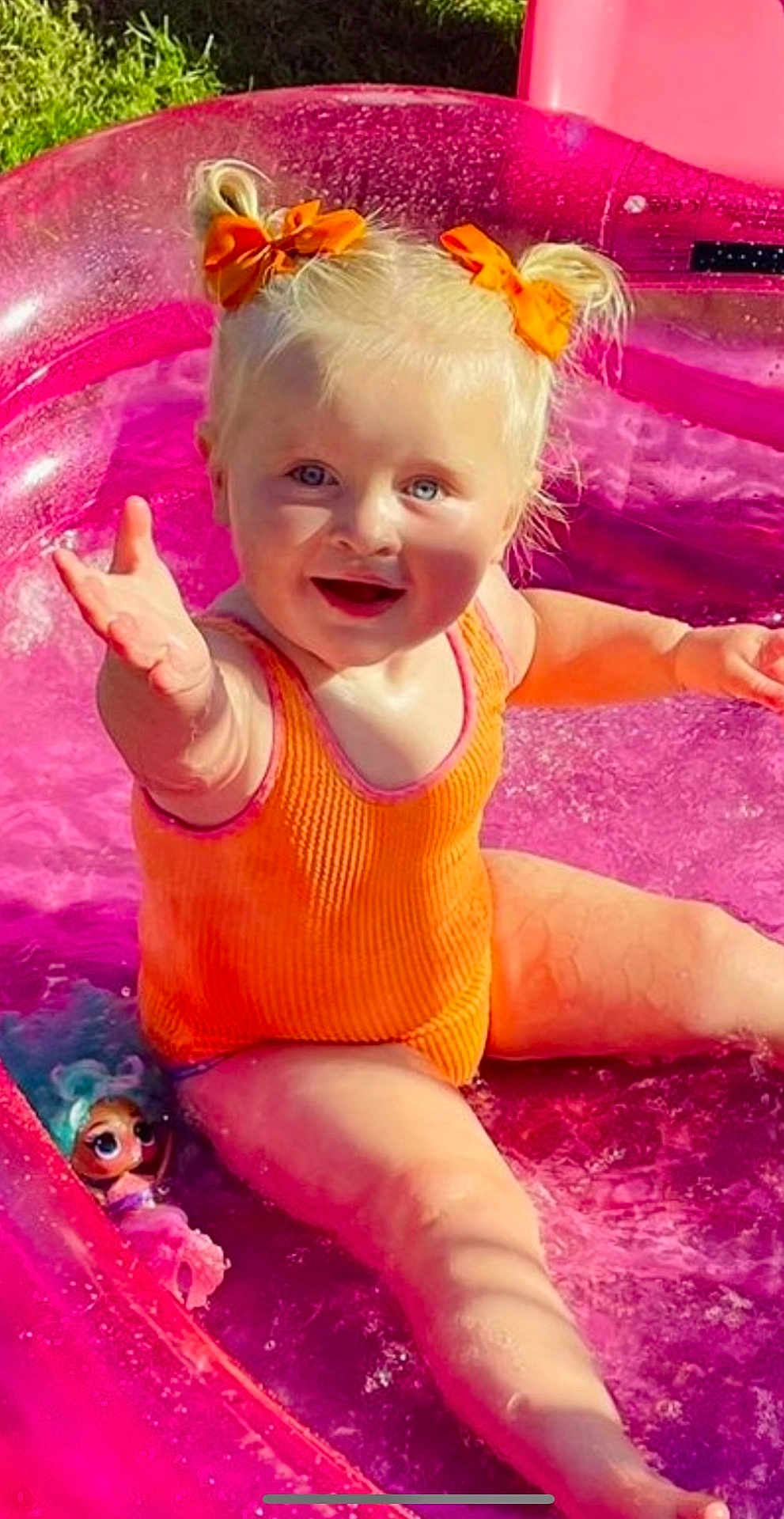 Darcey joined the competition — help win amazing prizes! toddler, child, swimsuit, orange, pink_pool, inflatable_pool, water, toy_doll, happy, smiling, blonde_hair, bows, summer, outdoor, splashing, sunlight, playtime, cute, baby, fun
