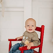 Colton joined the competition — help win amazing prizes! baby, blue_eyes, casual_clothing, child, cute, furniture, happy, holiday_decor, indoor, infant, jeans, mantle, neutral_background, portrait, red_chair, rocking_chair, seated, smiling, sweatshirt, toothy_grin