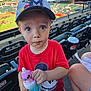 Colton is registered to the contest to win money with this photo: child, toddler, baseball_stadium, hat, mickey_mouse, red_shirt, drink_bottle, toy_topper, seating, spectator, outdoor, daylight, people, sports, cap, facial_expression, curious, event, crowd, plastic_bottle