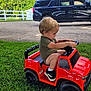 Gabriel is registered to the contest to win money with this photo: toddler, child, toy_truck, red_toy, grass, outdoor, sunny, greenery, black_suv, fence, side_view, short_hair, casual_clothing, sneakers, play, young_child, summer, daylight, vehicle, drive