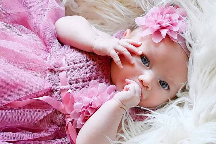 Esther is registered to the contest to win money with this photo: baby, baby_toddler_clothing, clothing, doll, dress, embellishment, eye, eyelash, hair, hand, head, headgear, headpiece, headwear, iris, lip, person, petal, pink, plant