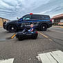 Ivan is registered to the contest to win money with this photo: baby, child, toy_car, police_car, police, vehicle, road, street, parking_lot, building, overcast, sky, urban, sidewalk, crosswalk, vehicle_lights, small_vehicle, outdoor, person, cute