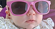 Esmeralda is registered to the contest to win money with this photo: baby, infant, child, sunglasses, pink_glasses, portrait, face, serious_expression, floral_clothing, bib, seated, car_seat, seatbelt, indoors, vehicle, close_up, fashion, accessory, baby_clothing, photograph