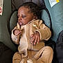 baby, infant, car_seat, clothing, onesie, nike, child, young_child, face, hands, cushion, warning_label, fabric, black_hair, indoor, comfort, seat, portrait, cute, resting