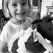 Nina participe au concours pour gagner de l'argent avec cette photo : child, smiling, indoor, stuffed_toy, plush, horse, happy, portrait, short_hair, white_shirt, toy, cute, young, person, face, holding, living_room, furniture, black_and_white, closeup
