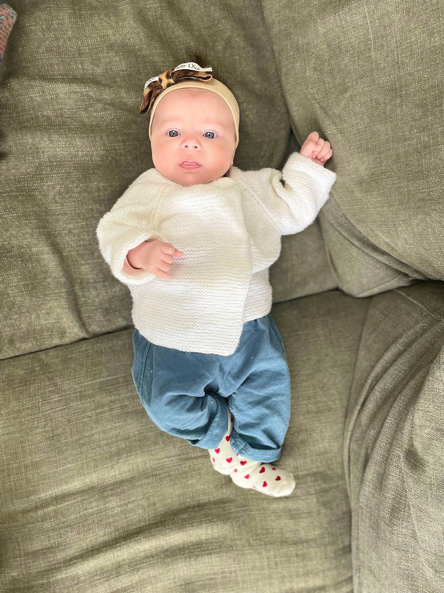 Nina a rejoint le concours — aidez-le/la à gagner de superbes lots ! baby, baby_products, baby_toddler_clothing, beanie, cheek, child, comfort, eye, fashion_accessory, linens, pattern, peach, person, sitting, skin, sleeve, sock, t_shirt, toddler, wood