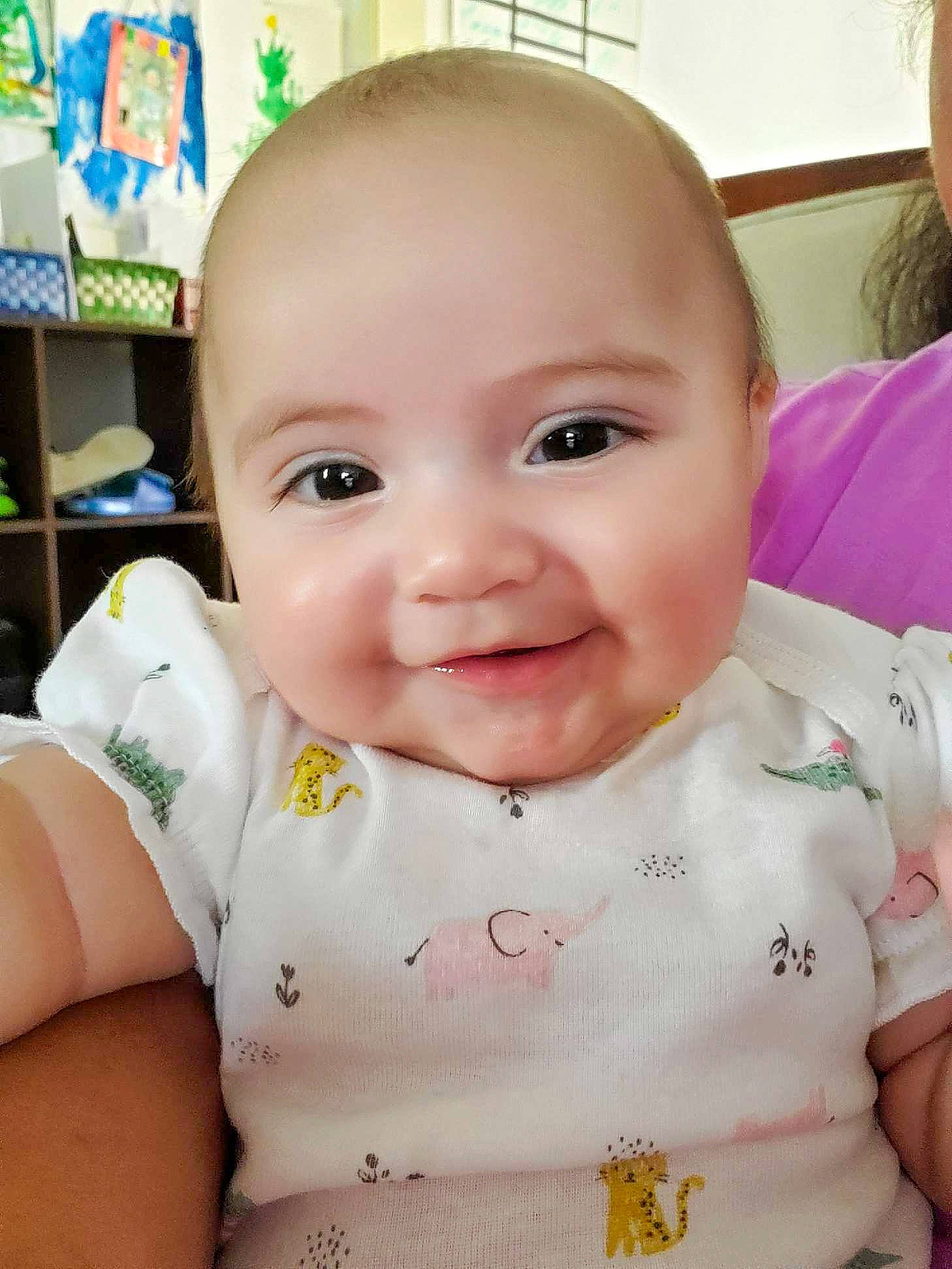 Kendra is registered to the contest to win money with this photo: baby, baby_toddler_clothing, cheek, chest, child, chin, eyelash, facial_expression, happy, iris, joy, lip, neck, pattern, person, product, shelf, sitting, skin, sleeve