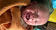 Cole joined the competition — help win amazing prizes! baby, infant, sleeping, yawning, face, portrait, close_up, bundled, orange_clothing, blanket, green_blanket, cozy, indoors, soft_lighting, peaceful, cute, baby_clothing, head, lying_down, photography