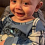 baby, child, smiling, face, blue_clothing, pajamas, plaid, happy, indoor, closeup, skin, person, head, eyes, mouth, infant, cute, comfort, sitting, warmth