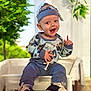 Rowan joined the competition — help win amazing prizes! baby, child, smiling, happy, outdoor, blue_outfit, hat, sitting, white_chair, greenery, plants, pointing, cute, footwear, nike_shoes, infant, portrait, daylight, playful, person