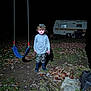 Jacobi is registered to the contest to win money with this photo: child, boy, night, swing, camouflage, cap, toy_car, boots, leaves, grass, camper, outdoor, dark, shadow, playground, toy, ground, person, fall, nature