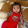 baby, infant, red_overalls, lightning_mcqueen, pillow, bed, blanket, clothing, person, cute, indoors, child, portrait, looking, hand, expression, soft_fabric, comfort, resting, young