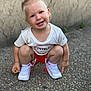 toddler, child, smiling, squatting, blue_eyes, white_tshirt, red_shorts, white_shoes, nike, outdoor, pebbled_ground, short_hair, happy, casual_clothing, person, cute, young_child, small_food, earrings, daylight