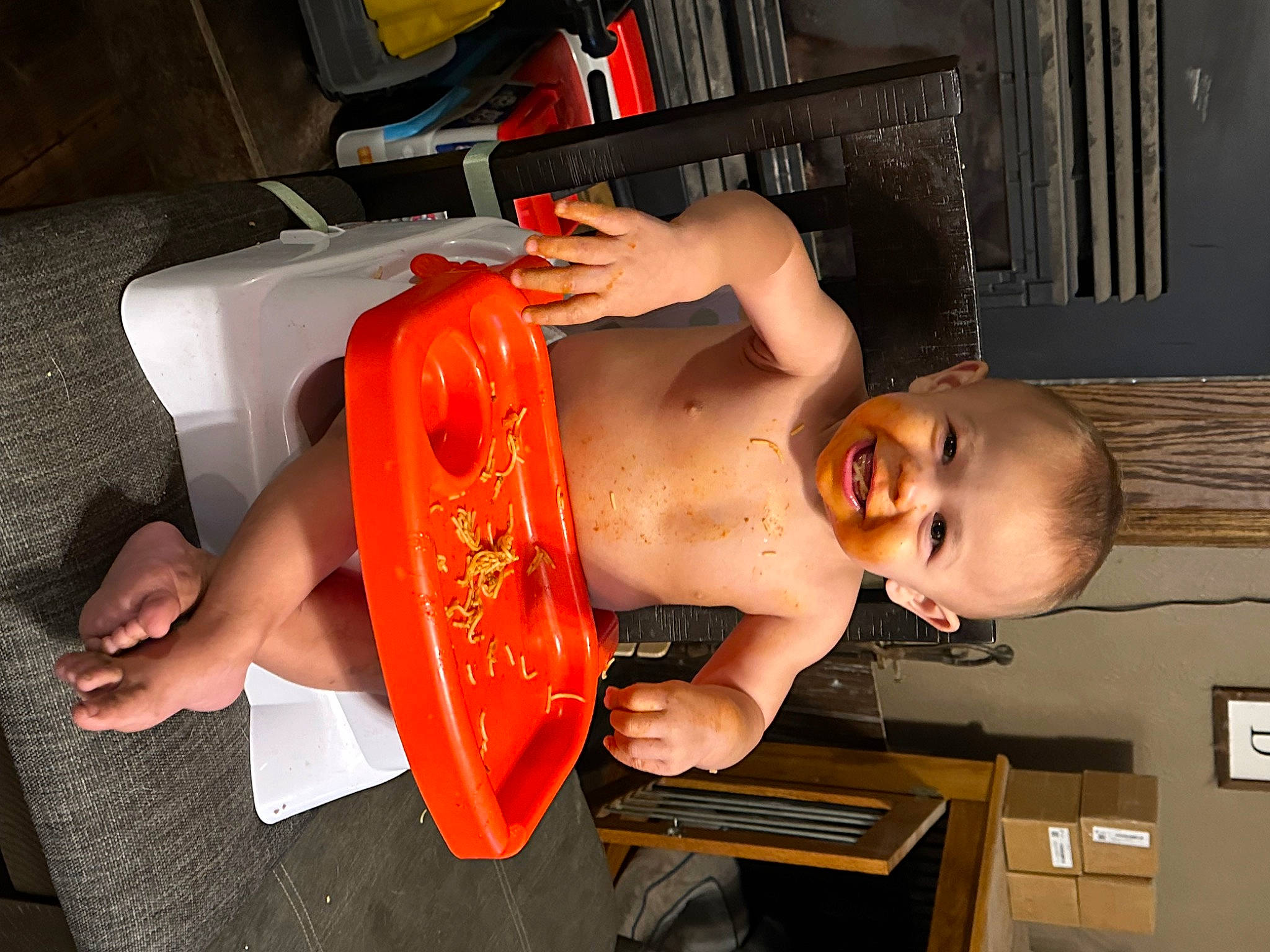 Justin is registered to the contest to win money with this photo: abdomen, chest, child, elbow, flesh, flooring, fun, human_leg, joy, machine, mouth, orange, person, room, sitting, smile, toddler, trunk, wood, wrist